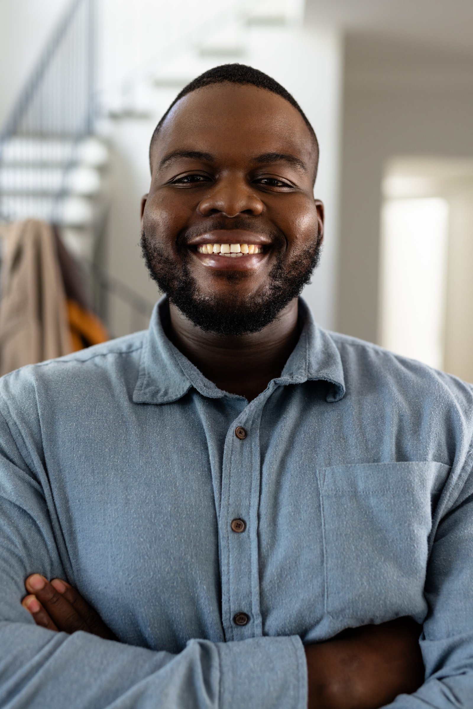 Portrait of happy african american man with short hair and arms crossed at home. Domestic life and lifestyle, unaltered.